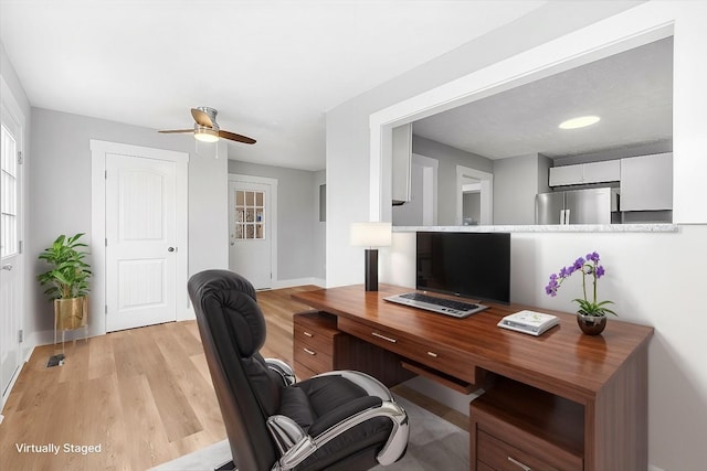 office featuring baseboards, ceiling fan, and light wood finished floors