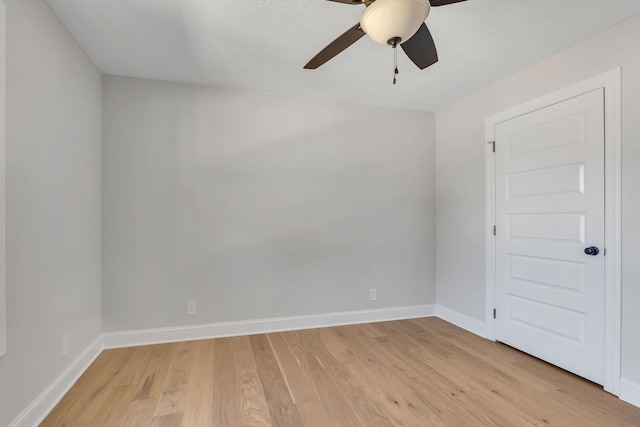 spare room featuring light wood-style floors, baseboards, and ceiling fan