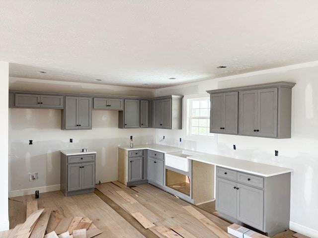 kitchen featuring light wood-type flooring, baseboards, and gray cabinets