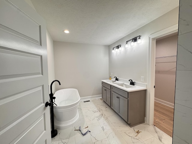 bathroom featuring baseboards, a walk in closet, marble finish floor, and a freestanding tub