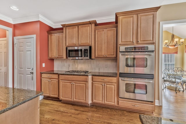1531 Pumpkin Ridge Ct, Nolensville, TN 37135 - kitchen featuring crown molding, dark stone countertops, stainless steel appliances, light wood-style floors, and an inviting chandelier