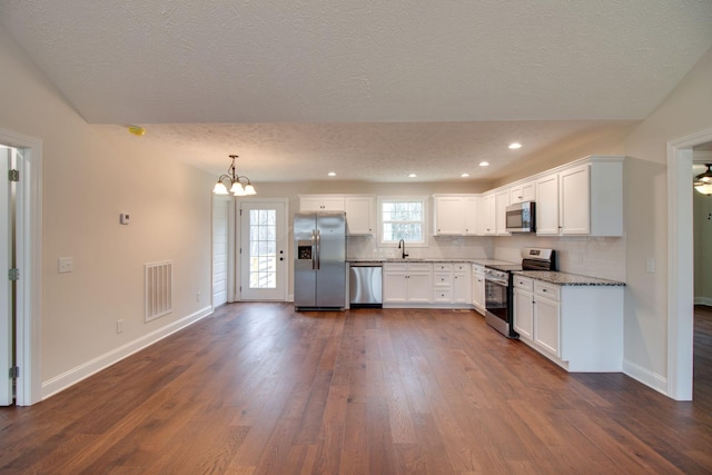 kitchen featuring visible vents, dark wood-style flooring, appliances with stainless steel finishes, a textured ceiling, and decorative backsplash