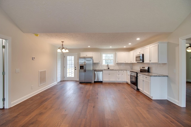 kitchen featuring tasteful backsplash, visible vents, dark wood finished floors, a textured ceiling, and stainless steel appliances