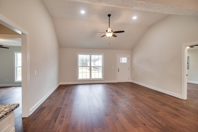 unfurnished living room featuring dark wood-type flooring, baseboards, a ceiling fan, and lofted ceiling