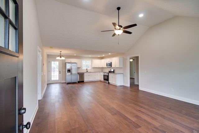 unfurnished living room featuring baseboards, high vaulted ceiling, dark wood-style floors, and ceiling fan with notable chandelier