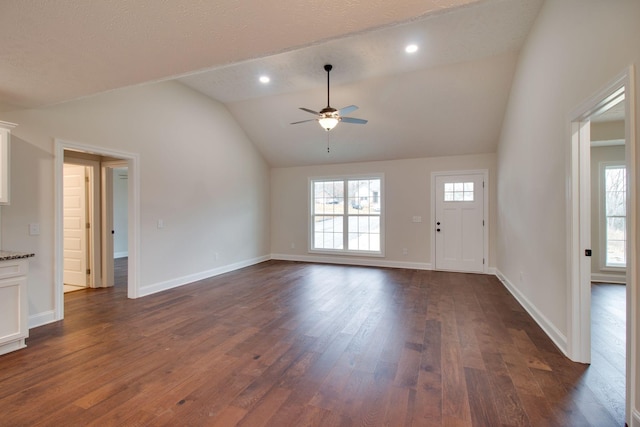 unfurnished living room featuring baseboards, a ceiling fan, vaulted ceiling, and dark wood-style floors