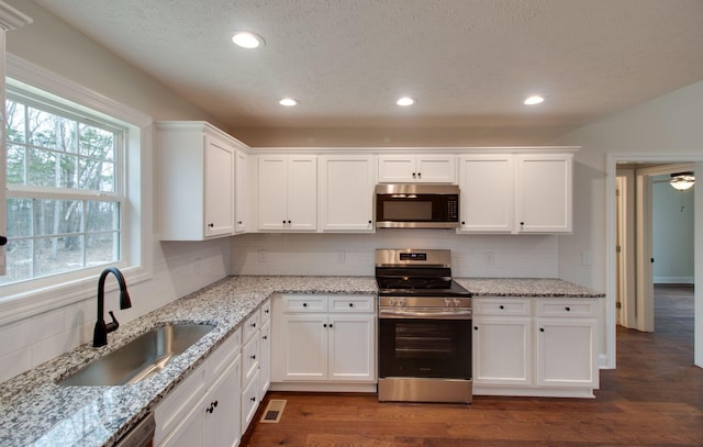 kitchen featuring tasteful backsplash, white cabinets, a sink, recessed lighting, and stainless steel appliances
