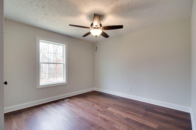 empty room featuring dark wood-type flooring, baseboards, a ceiling fan, and visible vents