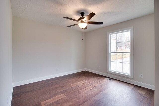 unfurnished room with dark wood-style flooring, a wealth of natural light, a ceiling fan, and baseboards