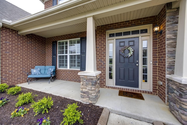 doorway to property featuring brick siding and covered porch