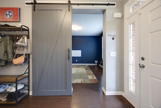 entrance foyer featuring wood finished floors, a healthy amount of sunlight, baseboards, and a barn door