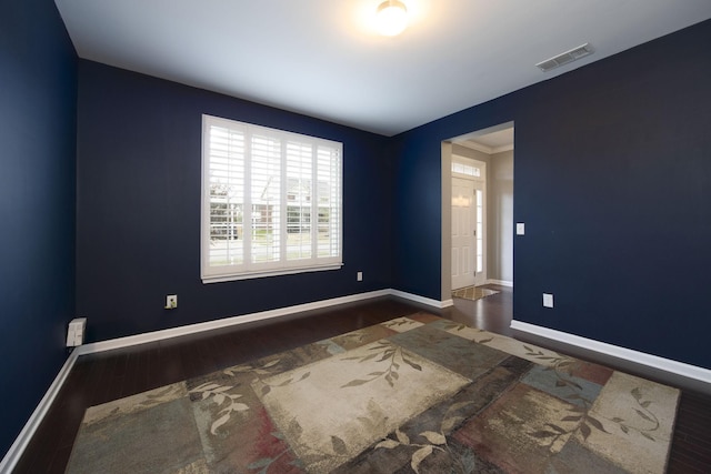 spare room with wood finished floors, baseboards, and visible vents