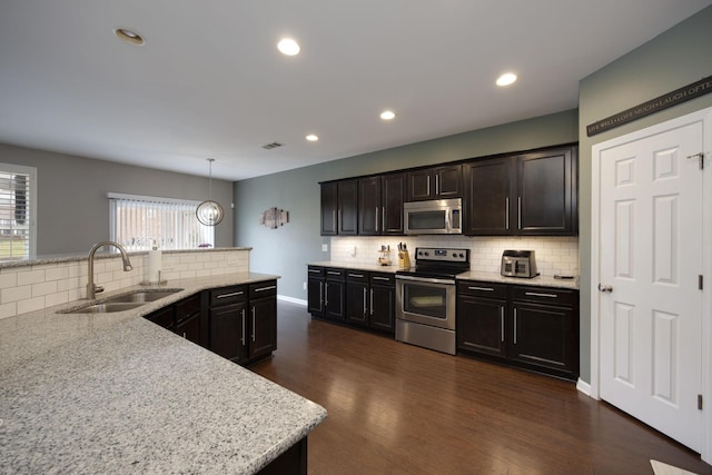 kitchen with dark wood-style floors, appliances with stainless steel finishes, a sink, and backsplash