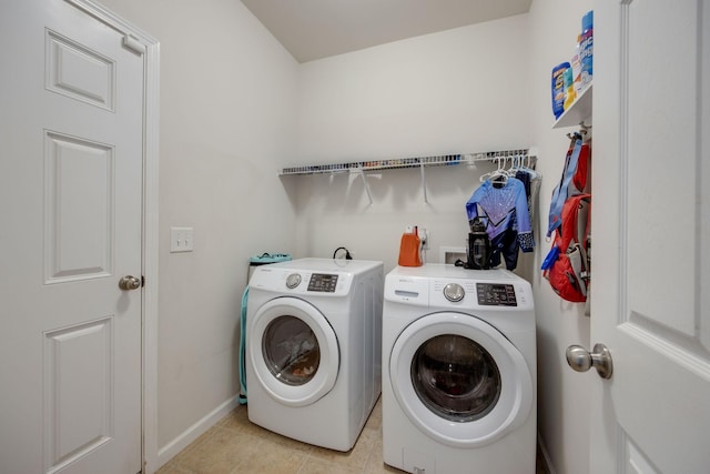 clothes washing area with light tile patterned floors, washing machine and dryer, laundry area, and baseboards