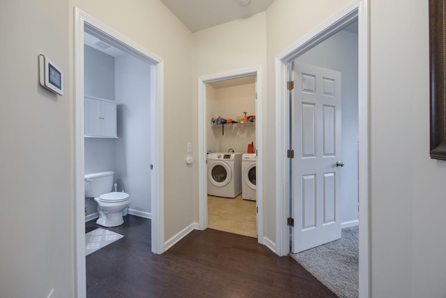 corridor featuring dark wood-type flooring, washing machine and dryer, and baseboards