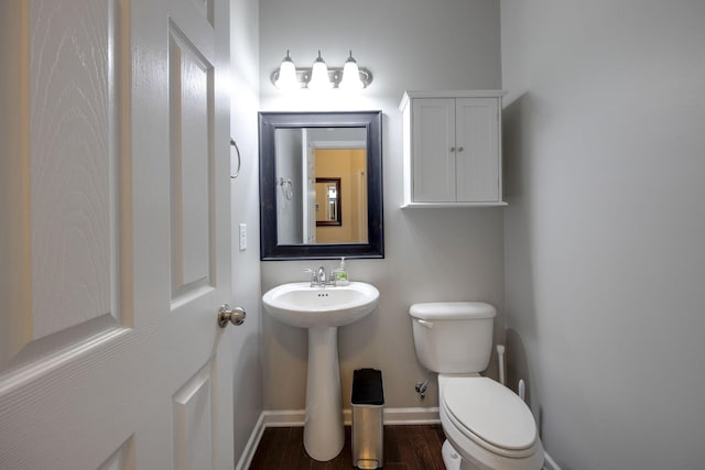 bathroom featuring toilet, wood finished floors, a sink, and baseboards