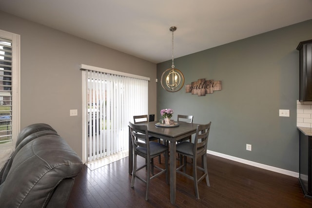 dining area with baseboards, an inviting chandelier, and dark wood finished floors