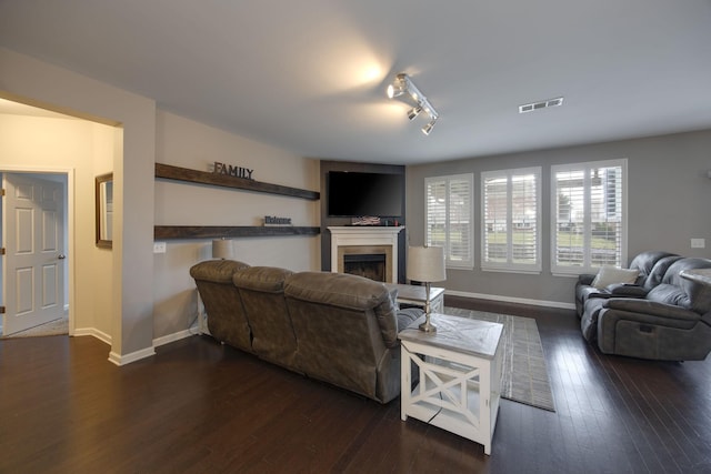 living room with a fireplace, hardwood / wood-style flooring, visible vents, and baseboards
