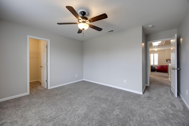 unfurnished bedroom with visible vents, a spacious closet, carpet floors, and baseboards