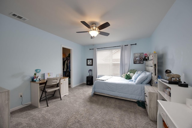 bedroom with baseboards, a ceiling fan, a walk in closet, visible vents, and light colored carpet
