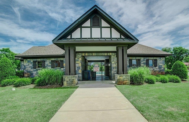 exterior space with a yard, a shingled roof, stone siding, and a standing seam roof