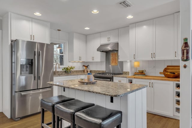 4337 Morriswood Dr, Nashville, TN 37204 - kitchen with appliances with stainless steel finishes, under cabinet range hood, white cabinetry, light wood-style floors, and a breakfast bar area