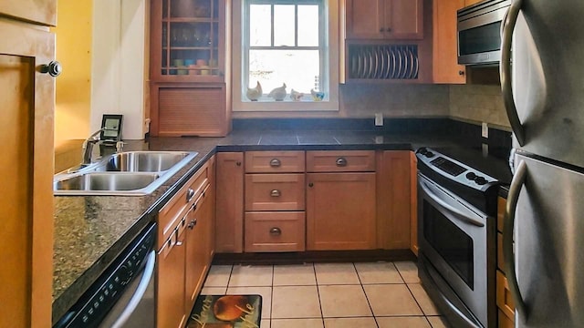 1385 Mitchell St, Celina, TN 38551 - kitchen featuring light tile patterned flooring, dark countertops, appliances with stainless steel finishes, a sink, and brown cabinetry