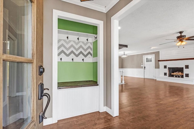interior space featuring a wainscoted wall, a textured ceiling, wood finished floors, and crown molding