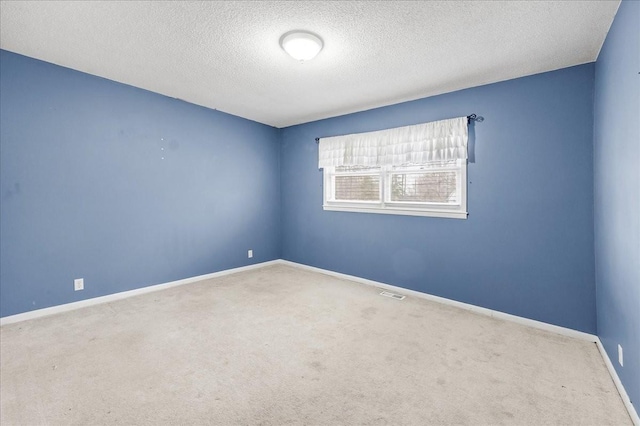 carpeted empty room featuring baseboards, a textured ceiling, and visible vents