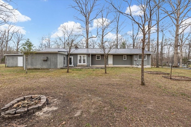 view of front facade with metal roof, a fire pit, french doors, and an AC wall unit
