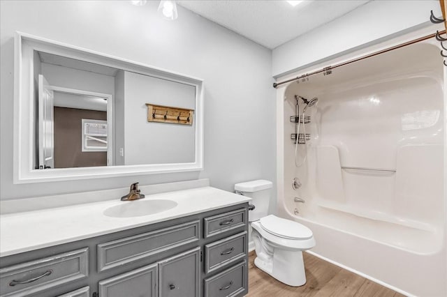 bathroom with a textured ceiling, wood finished floors, toilet, vanity, and shower / bath combination