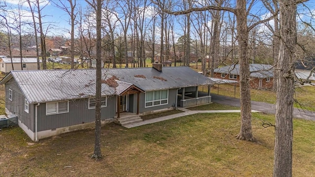 view of front of property featuring metal roof, crawl space, aphalt driveway, a front lawn, and a carport