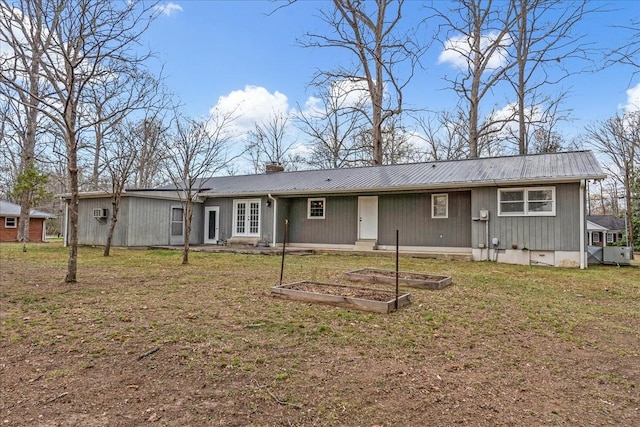 back of house with french doors, a chimney, a lawn, and metal roof