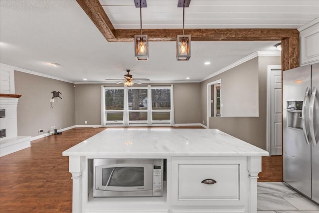 kitchen featuring crown molding, appliances with stainless steel finishes, open floor plan, baseboards, and ceiling fan