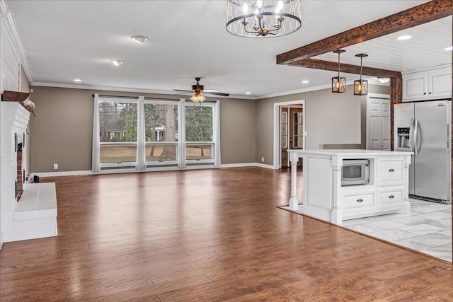 interior space featuring baseboards, ceiling fan with notable chandelier, beamed ceiling, and light wood-type flooring
