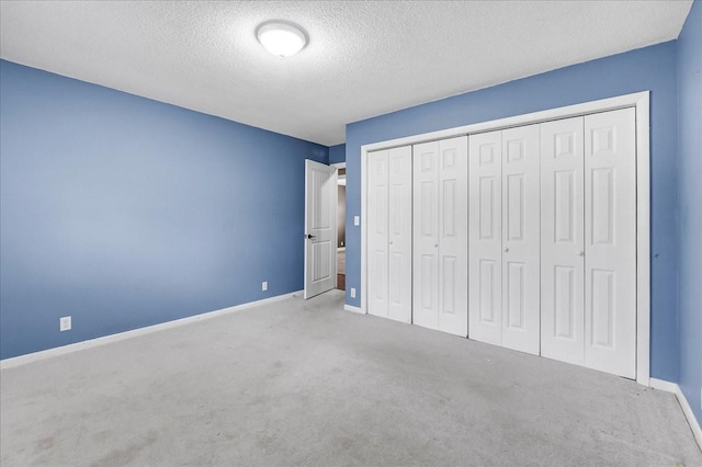 unfurnished bedroom with baseboards, carpet floors, a textured ceiling, and a closet