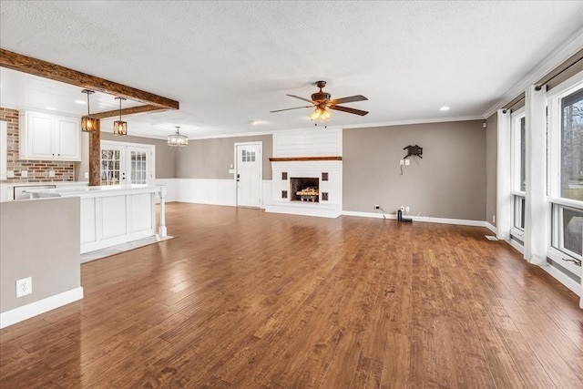 unfurnished living room featuring a wealth of natural light, a ceiling fan, wood finished floors, and a textured ceiling