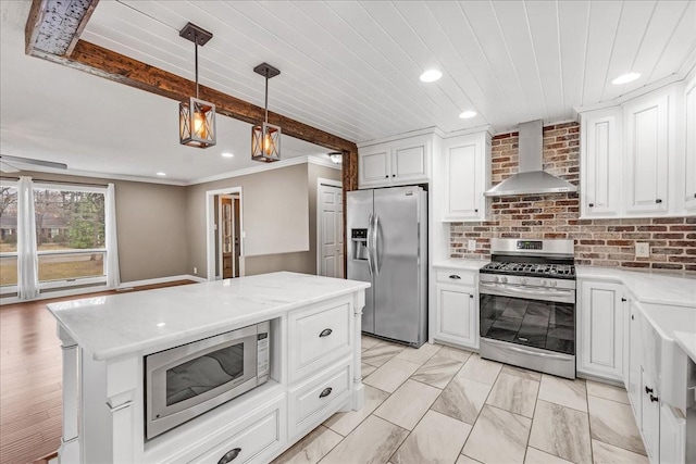 kitchen with white cabinetry, light countertops, hanging light fixtures, wall chimney range hood, and appliances with stainless steel finishes