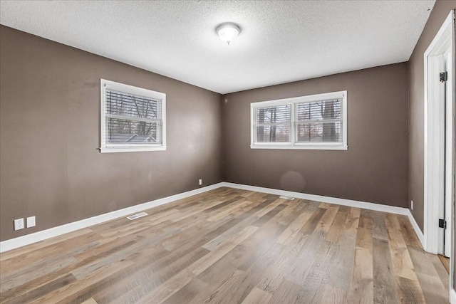unfurnished bedroom with baseboards, a textured ceiling, visible vents, and light wood-type flooring