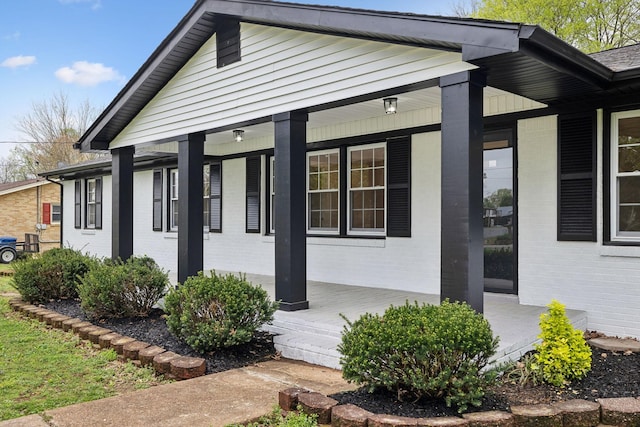 view of side of home featuring brick siding and a porch