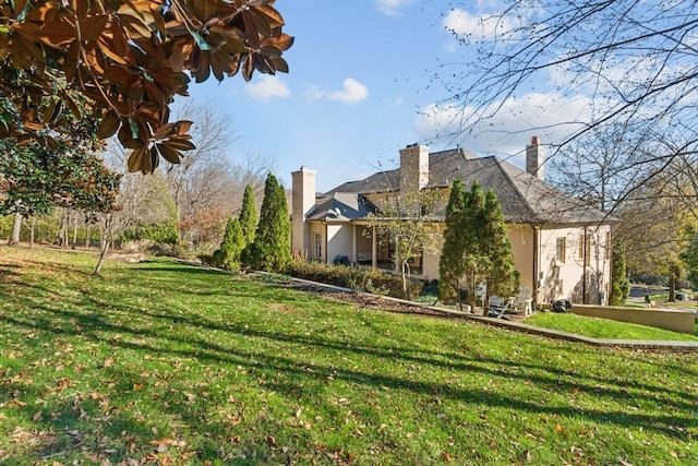 view of home's exterior with a chimney, stucco siding, and a lawn