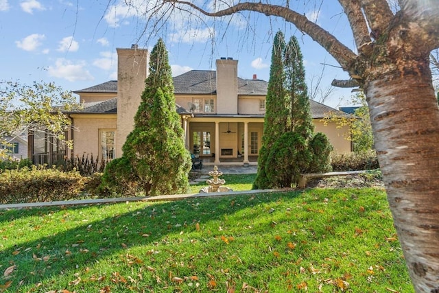 view of front of property featuring a chimney, ceiling fan, a front lawn, and french doors