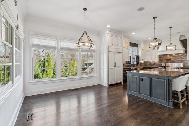 kitchen featuring a breakfast bar, dark wood-type flooring, white cabinetry, pendant lighting, and backsplash