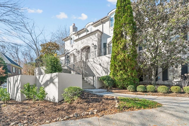 view of front of property with a chimney, stucco siding, and stairway