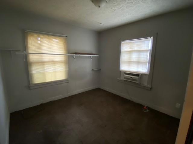 unfurnished room with baseboards and a textured ceiling