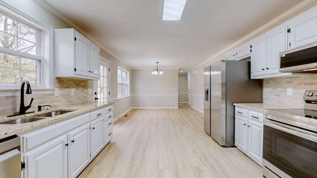 kitchen with crown molding, a sink, a chandelier, white cabinetry, and appliances with stainless steel finishes