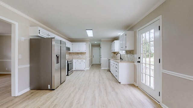 kitchen featuring crown molding, white cabinets, a sink, and stainless steel appliances
