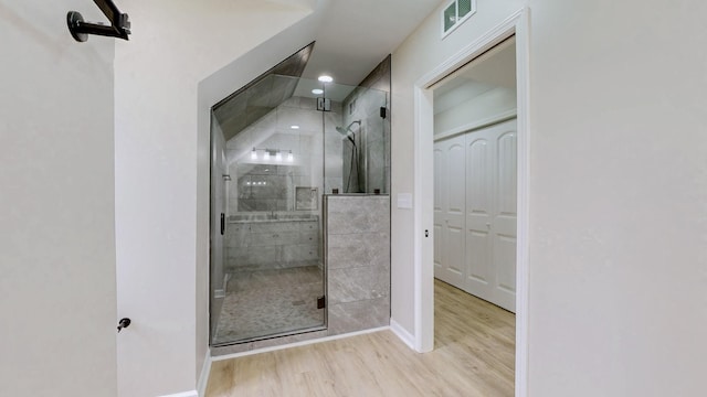 full bathroom featuring a stall shower, baseboards, visible vents, and wood finished floors