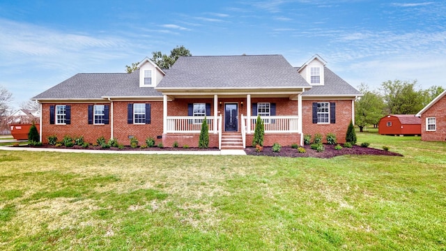 cape cod-style house with a front yard, a porch, brick siding, and roof with shingles