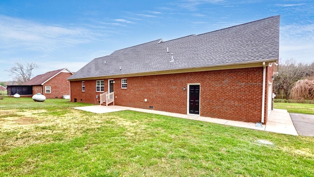 back of house featuring entry steps, brick siding, a shingled roof, a yard, and a patio area